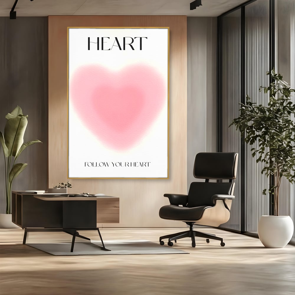Tablou canvas cu tablou vertical cu inima roz blurata, in rama de aluminiu auriu, pe perete intr-un birou